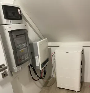 Espacio compacto con panel eléctrico, inversor solar y batería para gestión de energía renovable.