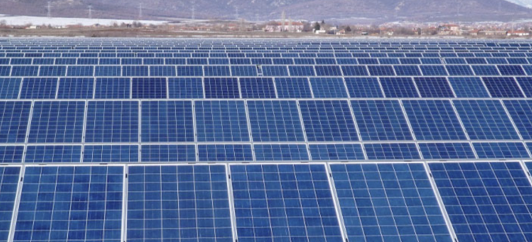 Campo de paneles solares en un paisaje montañoso, destacando la energía renovable y sostenibilidad.