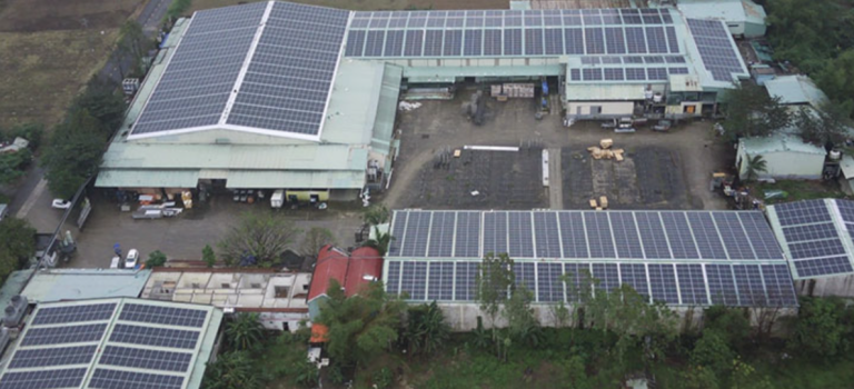 Complejo industrial sostenible con paneles solares, diseño funcional y vegetación circundante.
